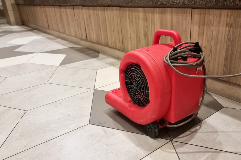 Technicians using industrial drying equipment to restore a water-damaged living room