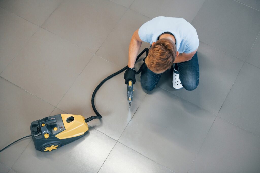 Top view of man in blue shirt and protective gloves that uses vacuum cleaner
